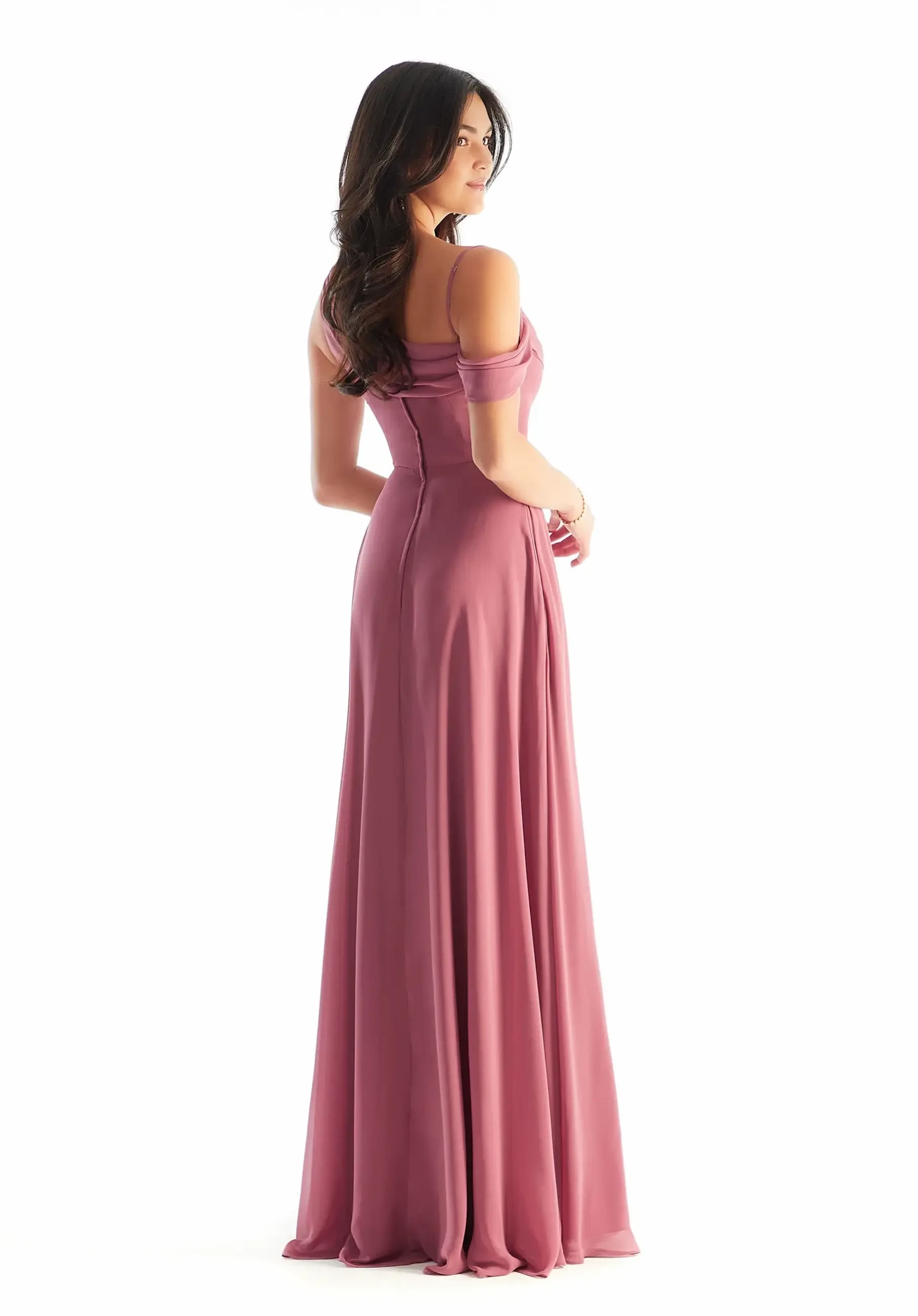 Model is wearing a chiffon A-line bridesmaid dress with an asymmetric cowl neckline, cold-shoulder draped sleeves, and a faux-wrap skirt with an off-center slit.