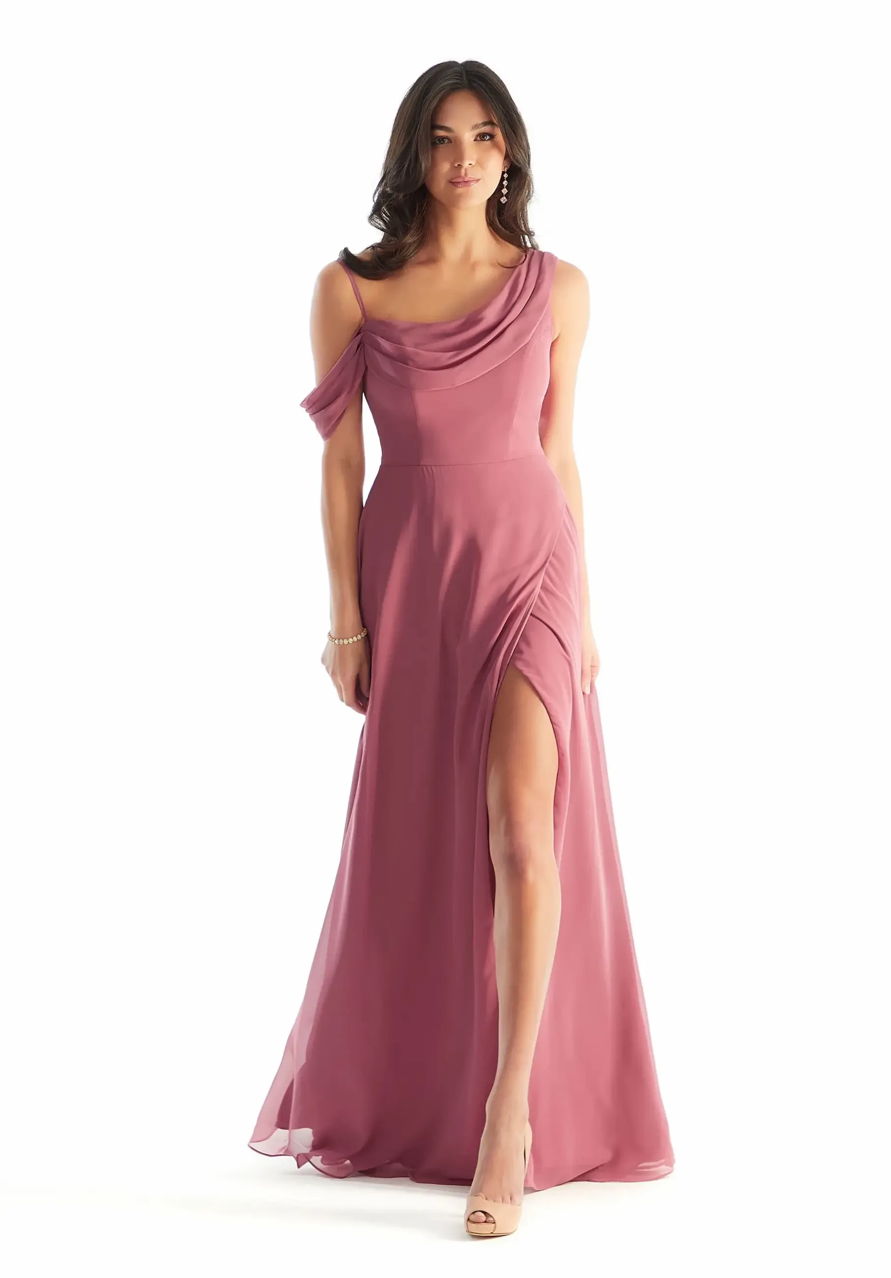 Model is wearing a chiffon A-line bridesmaid dress with an asymmetric cowl neckline, cold-shoulder draped sleeves, and a faux-wrap skirt with an off-center slit.