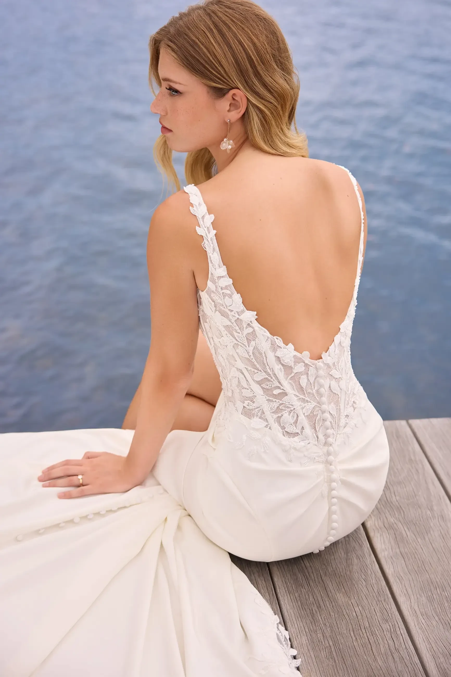 Model is wearing a sleek fit-and-flare gown featuring a semi-sheer corset bodice, high slit, and laser-cut lace details.